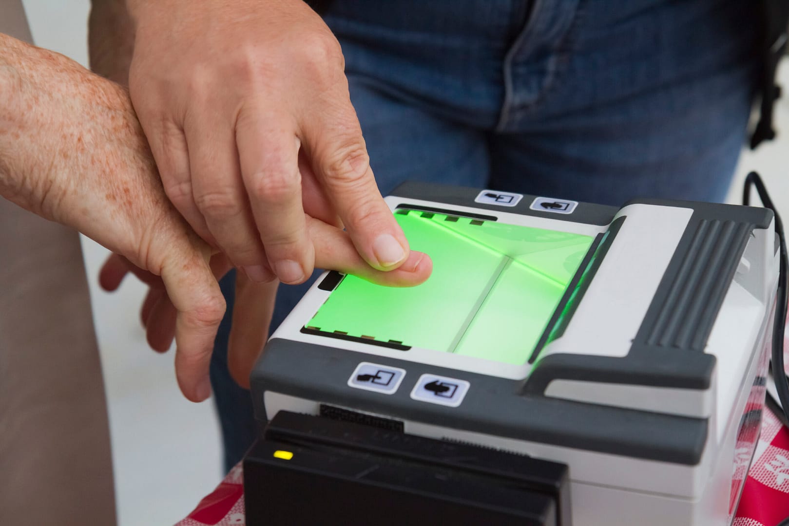 Man guiding another in using a fingerprint scanner