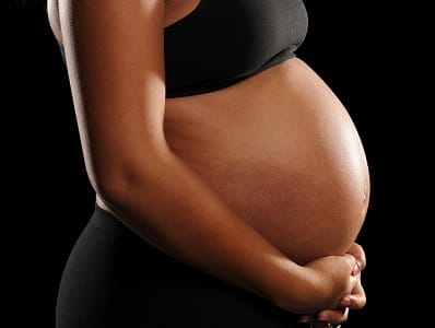 Young African American Woman Pregnant isolated on a black backgr