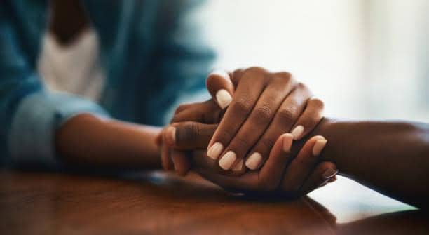 Closeup shot of two people holding hands in comfort