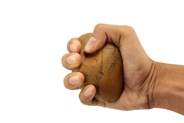 isolated mongoloid hand holding stone for throw on white