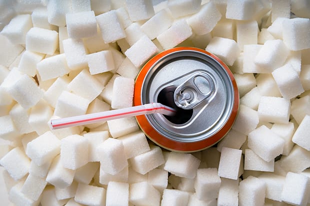 Carbonated soda drink with many sugar cubes. Unhealthy eating co